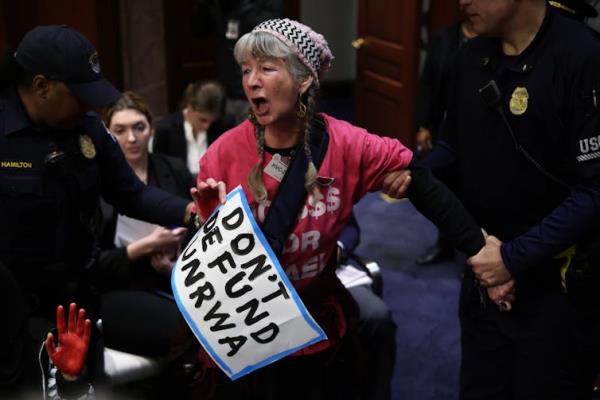 A woman holds a poster stating'Don't Defund UNRWA'